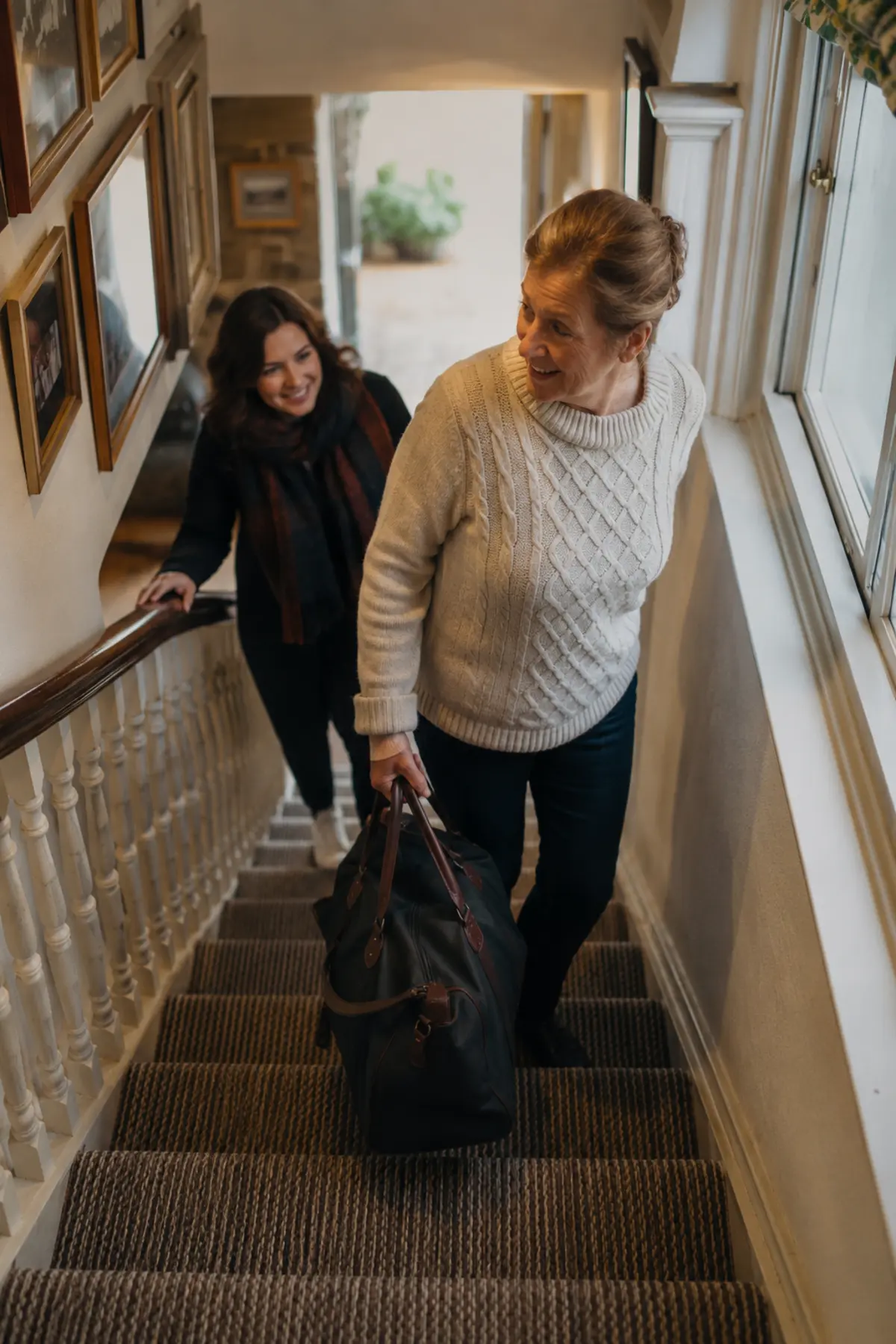 B&B owner carrying a guest's bag up the stairs